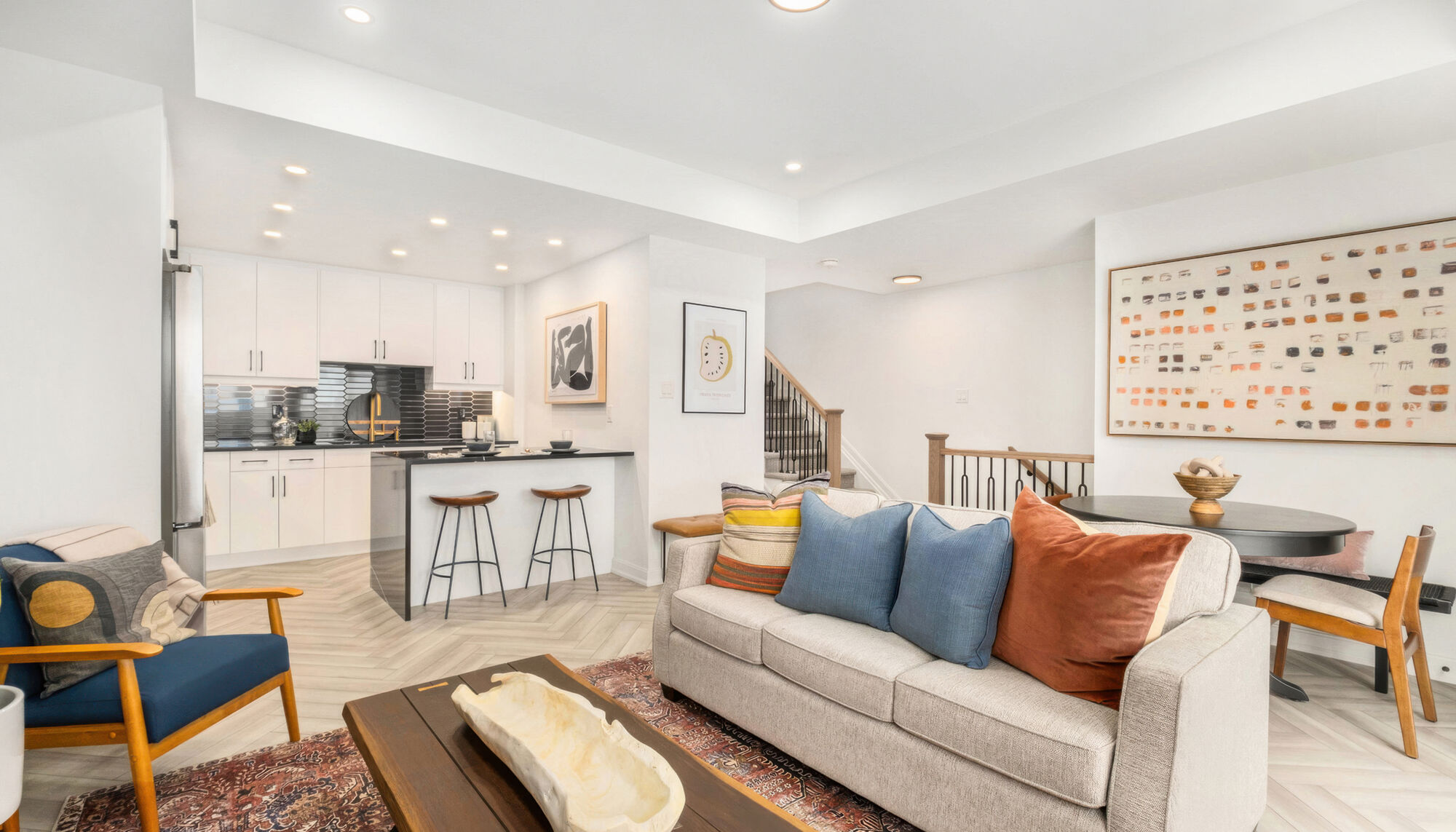 A furnished open-plan living room with a sofa and a kitchen beyond.