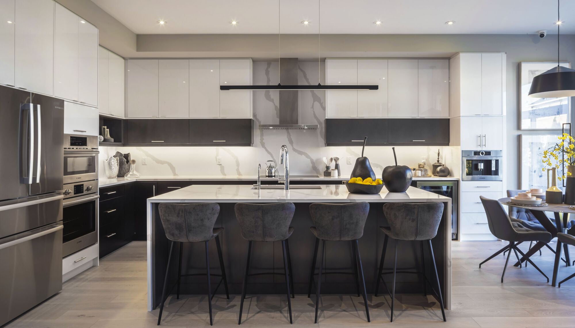 A kitchen with a broad island, dark lower cabinets and white upper cabinetry.